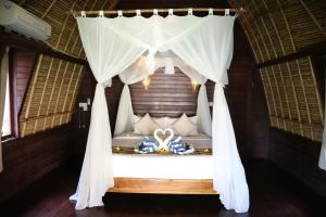 1 dormitorio con 1 cama con dosel blanco en MolaMola House, en Nusa Lembongan