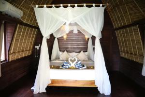 a bedroom with a bed with a white canopy at MolaMola House in Nusa Lembongan