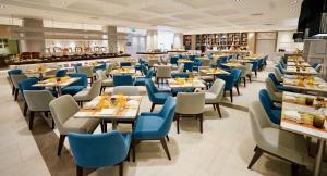 a dining room with tables and blue chairs at Amari Don Muang Airport Bangkok in Bangkok