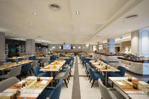 a restaurant with long tables and blue chairs at Amari Don Muang Airport Bangkok in Bangkok