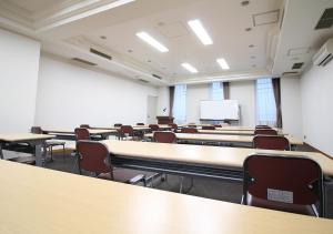 a large room with tables and chairs and a screen at Hotel Trend Funabashi in Funabashi