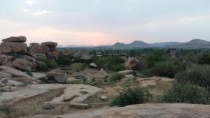 a group of rocks on a hill with mountains in the background at Riverside Homestay in Hampi