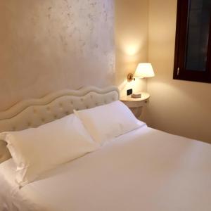 Un dormitorio con una cama blanca y una lámpara en una mesa en Cà Doge, en Venecia