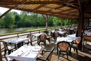 a restaurant with white tables and chairs and a river at Logis Hôtel Restaurant Beau Rivage in Saint-Baudelle +5 photos