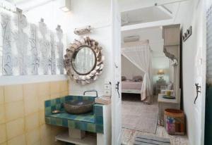 a bathroom with a sink and a mirror and a bed at Palmeto Village in Gili Trawangan