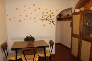 uma sala de jantar com uma mesa e uma árvore com folhas na parede em Casa Velia em Uzzano
