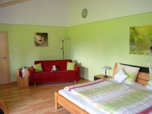 a bedroom with a bed and a red couch at Ferienhof Nirschl in Winzer