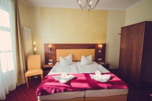 a hotel room with a bed with two white flowers on it at Hotel Arena City in Leipzig