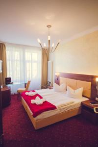 um quarto de hotel com uma cama grande e um cobertor vermelho em Hotel Arena City em Leipzig