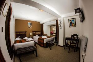 普諾的住宿－孔德萊莫斯酒店，酒店客房带两张床和一张桌子以及椅子。