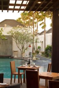 a table with a bottle of wine and chairs next to a pool at Daluman Villas in Seminyak