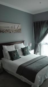 a bedroom with a large bed and a window at Garden Gate Guest House in Port Elizabeth