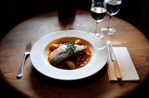 a bowl of food on a table with wine glasses at Compasses Inn in Tisbury