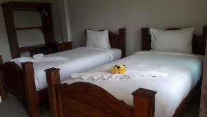twee bedden met witte lakens en een pompoen erop bij Suksopha Resort in Prachuap Khiri Khan