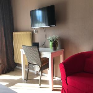 einen weißen Tisch mit einem Stuhl und einen TV an der Wand in der Unterkunft Bel'vue in Lienz