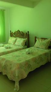 two beds in a room with green walls at Quartos Praia do Foguete Cabo Frio in Cabo Frio