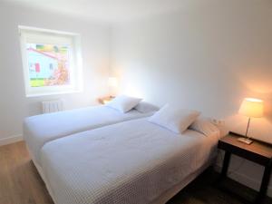 2 camas en una habitación con 2 lámparas y una ventana en Maison Oyan, en Urrugne