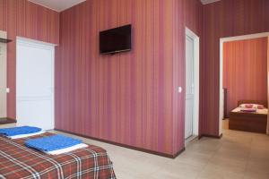 a bedroom with a red wall with a tv on it at Reskator Hotel in Adler