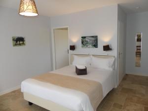 Un dormitorio blanco con una cama blanca con una caja. en Maison d' Hôtes L'Aria Mezzana, en Sainte-Lucie de Porto-Vecchio