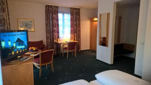 a hotel room with a tv and a table with chairs at Hotel Marxzeller Mühle in Marxzell