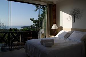 a bedroom with a bed and a large window at Costa do Sol Boutique Hotel in Búzios