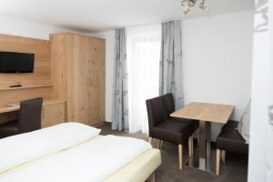 a room with a bed and a table and chairs at Pension Irlingerhof in Mondsee