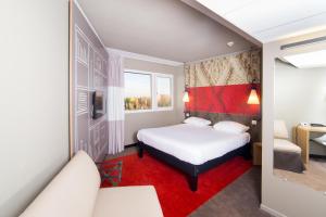 a hotel room with a bed and a red rug at Ibis Toulouse Purpan Aeroport in Toulouse