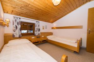 a bedroom with two beds and a wooden ceiling at Haus Fercher in Grossarl