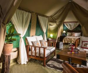 a room with a tent with a bed and a couch at Losokwan Luxury Tented Camp - Maasai Mara in Aitong