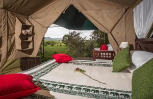 a bed in a tent with red and green pillows at Losokwan Luxury Tented Camp - Maasai Mara in Aitong