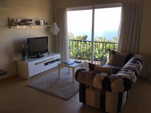 a living room with a couch and a television and a balcony at Villa Atlantis in Calheta