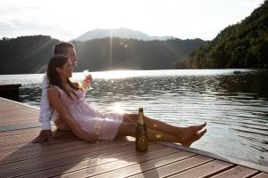 a man and woman sitting on a dock with a bottle of wine at Grand Hotel Imperial in Levico Terme