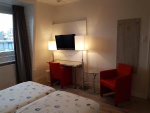 a hotel room with a bed and a desk and a tv at Hotel Bor Scheveningen in Scheveningen