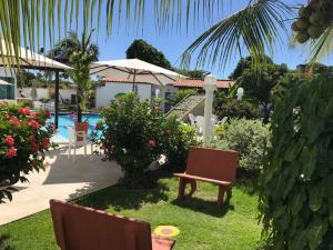 a garden with a bench and a swimming pool at Portoparadise - Mandakaru Residence Flat 10 in Porto De Galinhas