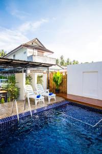 a swimming pool with two chairs and a house at S2 Residence in Ao Nang Beach