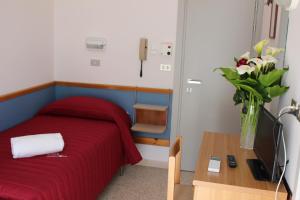 sypialnia z czerwonym łóżkiem i stołem z wazonem kwiatów w obiekcie Hotel Emma w mieście Cattolica