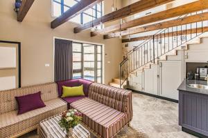 a living room with a couch and a staircase at Gold 68- גולד 68 סוויטות בוטיק in Kefar Barukh