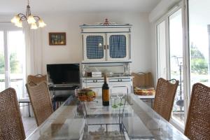 uma sala de jantar com uma mesa de vidro e uma televisão em Jardin du Bourg em Lanton