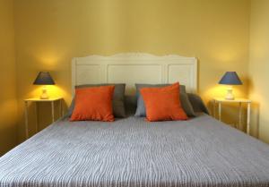 - une chambre avec un lit doté d'oreillers orange et de 2 lampes dans l'établissement Jardin du Bourg, à Lanton