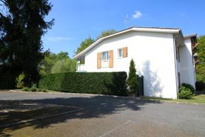 una casa blanca con un seto delante de ella en Jardin du Bourg, en Lanton