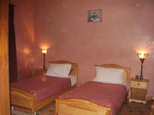 two beds in a room with two lights on the wall at Residence Essaouira Mogador in Essaouira
