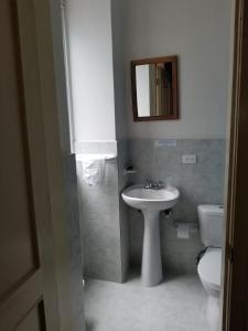 a bathroom with a sink and a toilet and a mirror at Heritage Inn in Quito