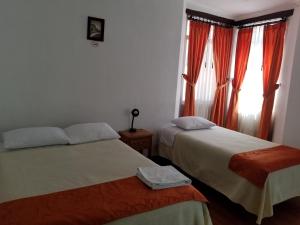 a bedroom with two beds and a window with curtains at Heritage Inn in Quito