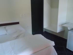 a bedroom with two white beds and a sink at Vitalliti Hotel in Alta Floresta