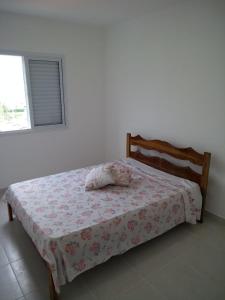 a bedroom with a bed with a floral bedspread at Condominio Garden Indaia in Caraguatatuba