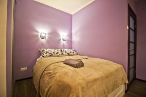 モスクワにあるLakshmi Apartment Novy Arbat 1kの紫の壁のベッドルーム1室、ベッド1台(茶色の毛布付)