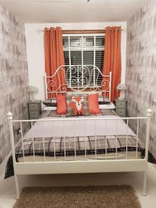 a white bed in a bedroom with orange curtains at Rooms at Tarrareoch in Bathgate