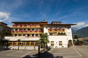 a large white building with balconies on a parking lot at Hotel Löwenwirt in Cermes