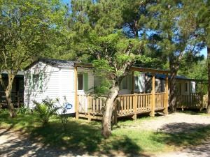 a small white house with a porch and trees at Camping de la Chapelette in Saint-Martin-de-Crau