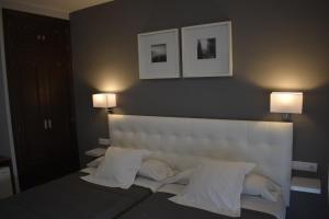 a bedroom with a large white bed with two lamps at Hostal el Rocio in Paracuellos de Jarama